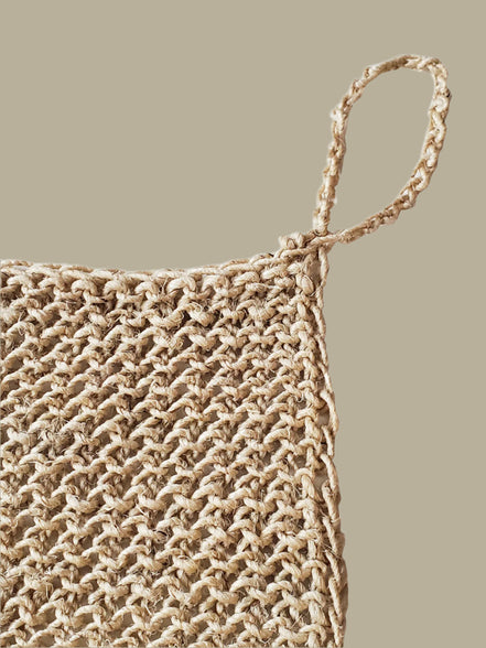 Close-up of a woven natural hemp washcloth with a handle on a white background