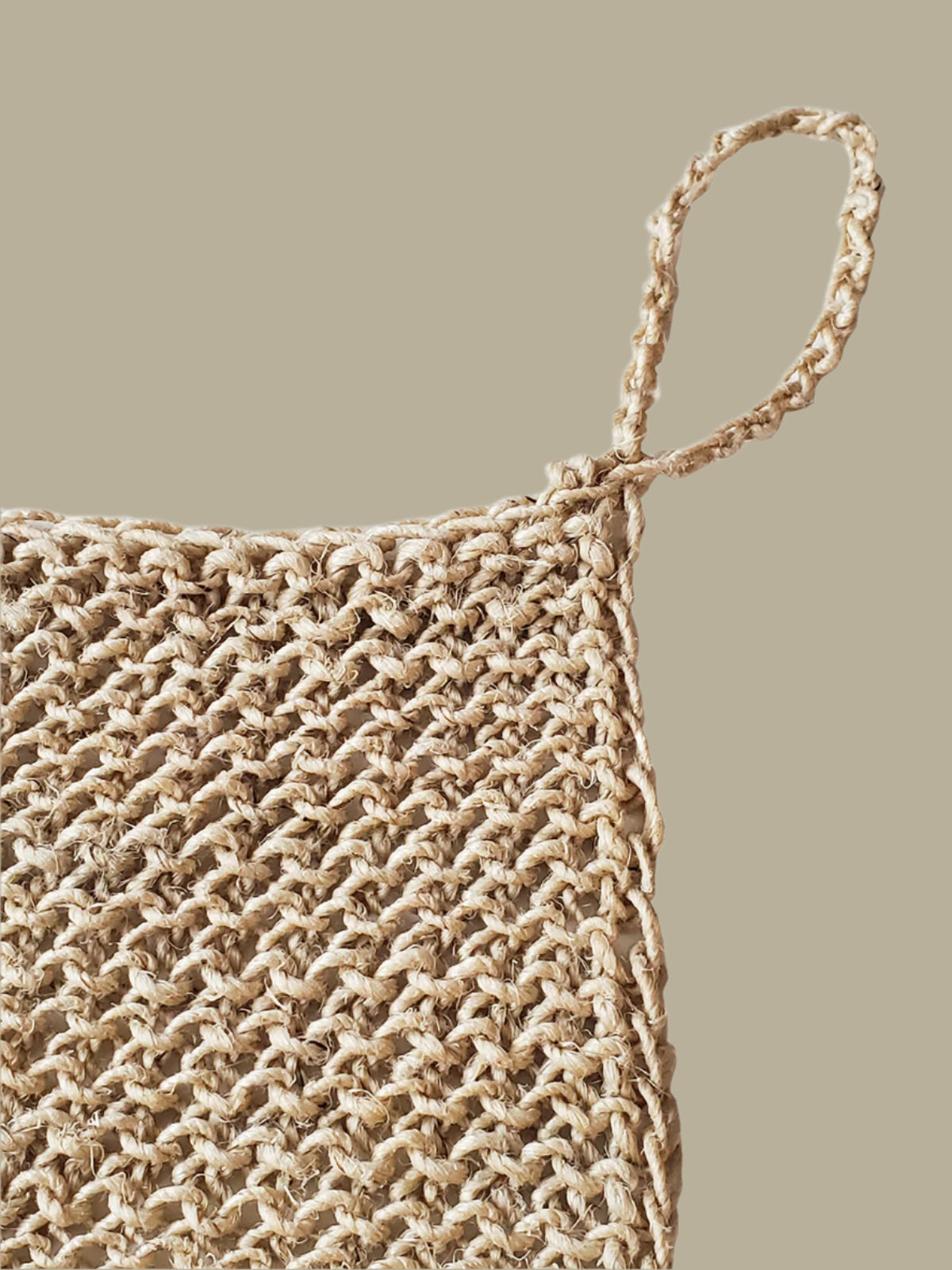 Close-up of a woven natural hemp washcloth with a handle on a white background
