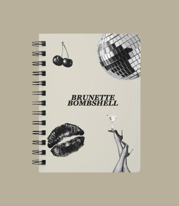 Notebook with 'Brunette Bombshell' design featuring a disco ball, cherries, lips, and a hand holding a cocktail.