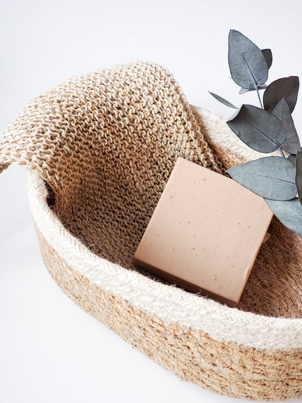hemp wasclothes in a woven basket with a textured cover and decorative leaves on a light background