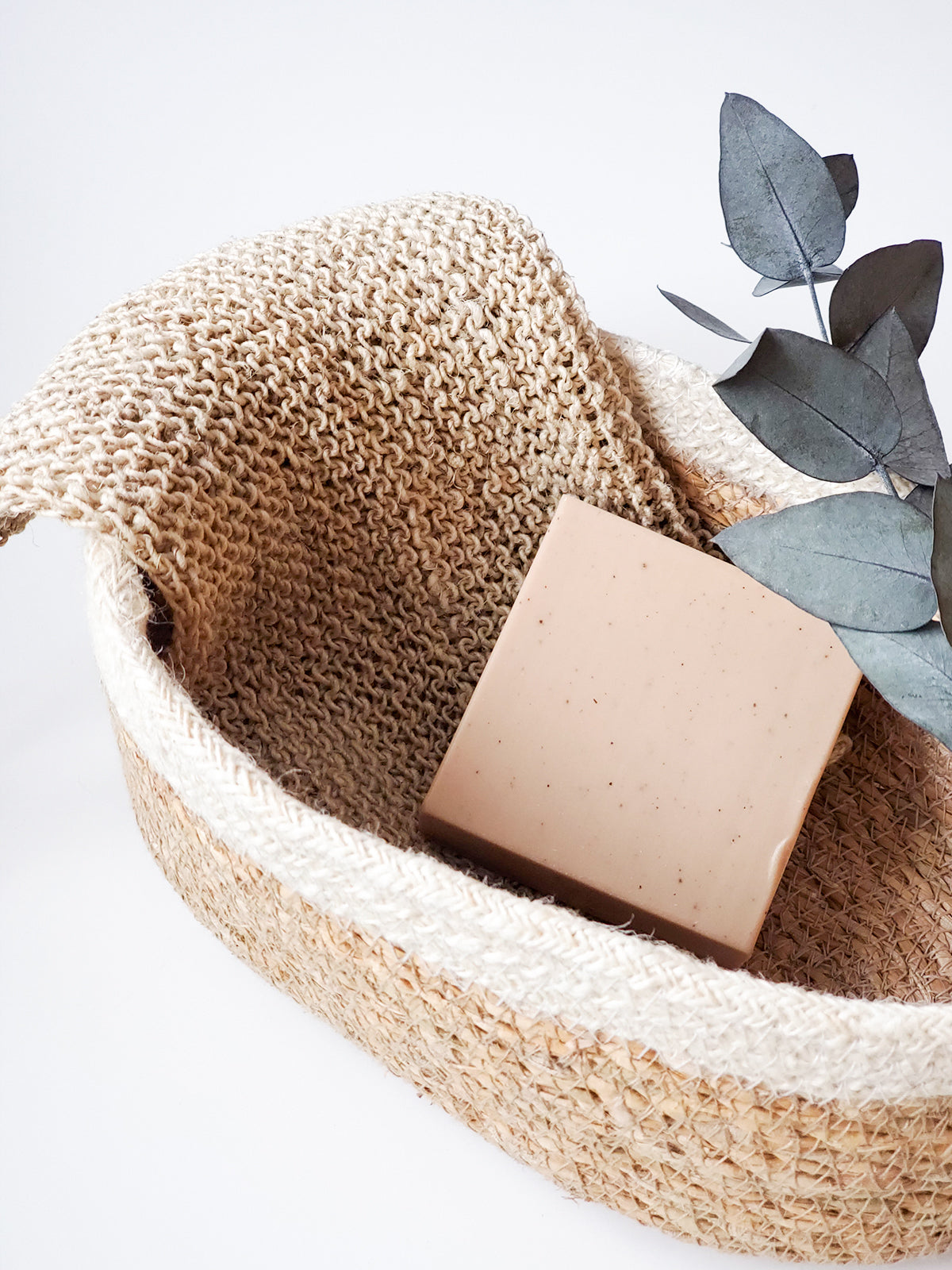 hemp wasclothes in a woven basket with a textured cover and decorative leaves on a light background