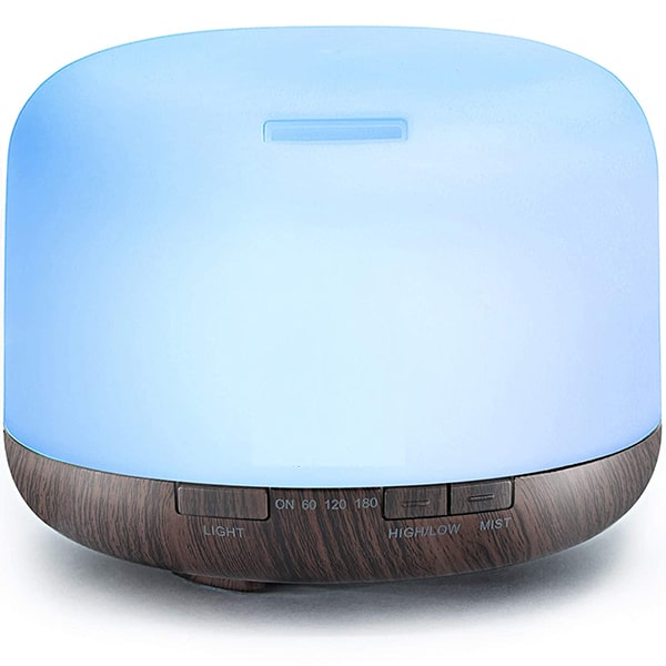 Aromatherapy diffuser with wooden base and blue light on a white background