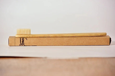 Bamboo toothbrush on a cardboard box with a plain background