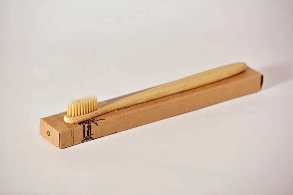 Bamboo toothbrush with packaging on a light gray background