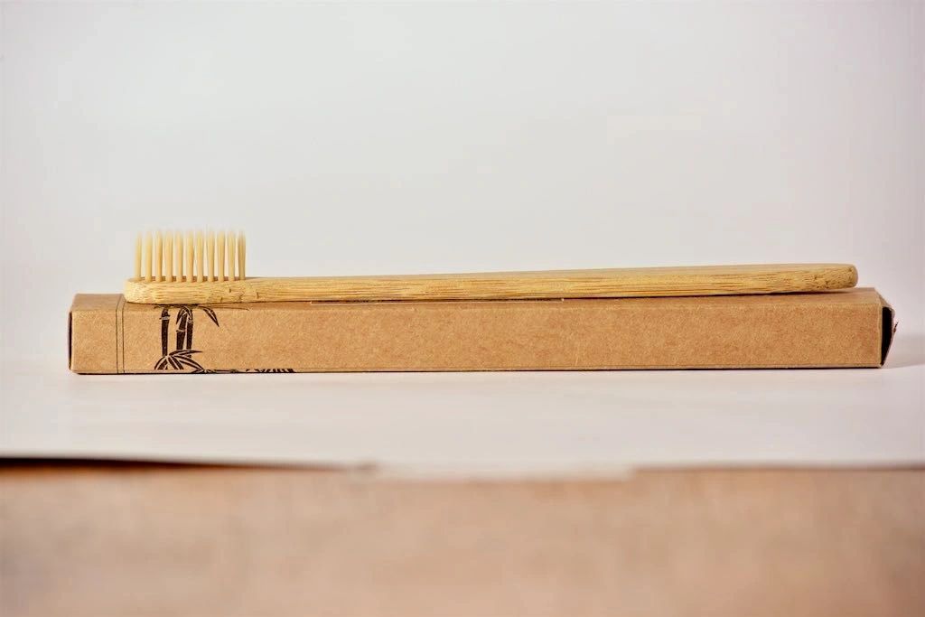 Bamboo toothbrush on a cardboard box with a plain background
